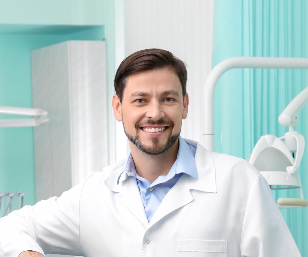 Professional male dentist in white coat at workplace
